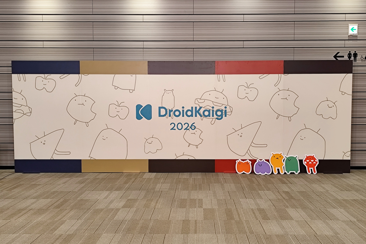 会場に設置されたDroidKaigi 2026のフォトスポット。手描き風のキャラクターが並ぶ大きなロゴパネルの足元に、色とりどりのキャラクターのパネルが立てかけられている。